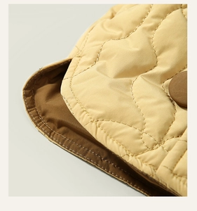 Detail of yellow quilted children coat featuring wave stitching and brown round button