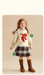 Détail de l'ensemble avec gilet en tricot, chemise bouffante, jupe écossaise et bottes brunes