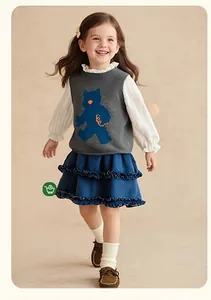 Détails d'un gilet en tricot pour filles avec motif ours et chemisier à col volanté