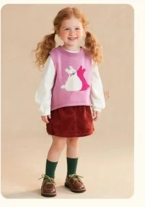 Détail du gilet en maille rose avec motif lapin et jupe en velours côtelé rouge