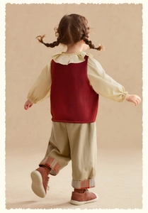 Détail du gilet en tricot pour enfant avec chemise à volants et pantalon à rayures