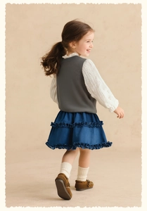 Détail du gilet en tricot pour fille avec chemise à volants et jupe marine à volants