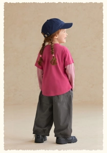 Seitenansicht eines Mädchen-Outfits mit einem rosa T-Shirt und grauen Freizeithosen
