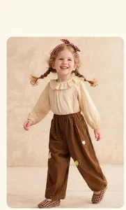Detail of kids corduroy pants with colorful embroidery and ruffle collar shirt set