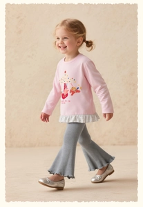 Détail d'un t-shirt rose à manches longues avec motif carrousel et volants fleuris