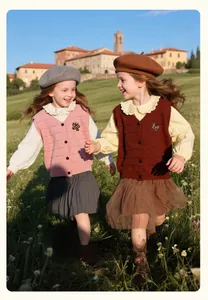 Detail of girls' knit vests featuring V-neck buttons and black butterfly embroidery