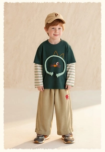Detail eines grünen Kinder-Langarmshirts mit 3D-Katze und lässiger hellbrauner Hose