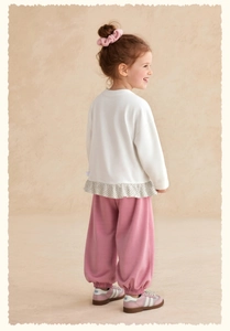 Détail du haut blanc à manches longues pour filles avec ourlet volanté à pois