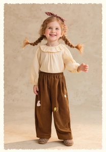 Detail of girls brown corduroy wide-leg trousers with cute embroidered patch details