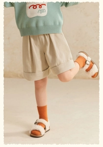 Detail view of girls corduroy shorts and green knitted sweater with wavy embroidery