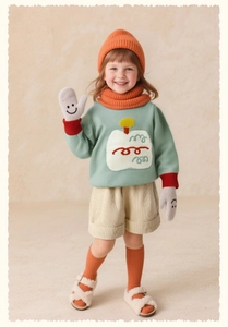 Detailed view of child's green knit sweater and beige corduroy shorts with warm accessories