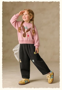Detail of pink sweatshirt with rabbit embroidery and black corduroy trousers for kids