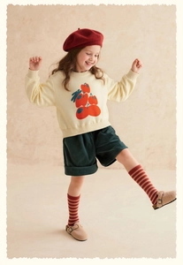 Full view of girl's retro outfit with green corduroy shorts and yellow sweatshirt