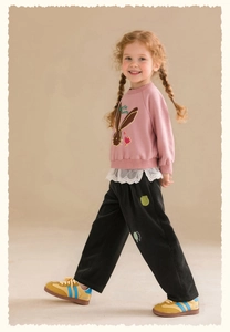 Detail of pink sweatshirt with rabbit embroidery, lace hem, and black corduroy pants