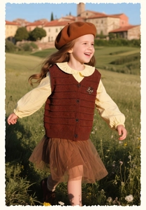 Detail of sweet girls knit vest with butterfly embroidery and ruffled shirt