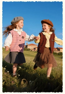 Detail of sweet girls' knit vests with butterfly accents in pink and caramel colors
