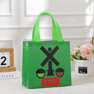 Detail of green non-woven shopping bag featuring a red STOP sign and railway signal pattern