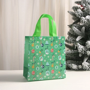 Detailed view of a green Christmas non-woven gift bag with festive snowman and bell patterns