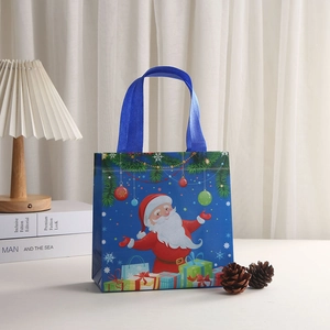 Blue Christmas non-woven gift bag with Santa Claus print shown in cozy holiday setting