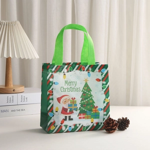 Close-up of non-woven Christmas gift bag with Santa Claus print and green handles