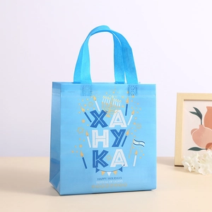 Blue Hanukkah non-woven gift bag with Happy Holidays candles print and ribbon handles