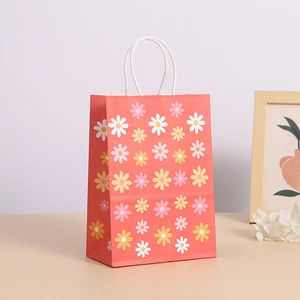 Bolsa de regalo de papel kraft rosa con patrón de margaritas y asas de cuerda blanca