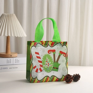 Detail of green Christmas non-woven gift bag with festive JOY lettering and candy cane