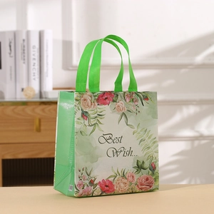 Detail of a floral non-woven gift bag with Best Wish text and green handles in a home setting
