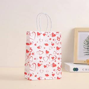 White kraft paper gift bag with red heart patterns and sturdy twisted white rope handles