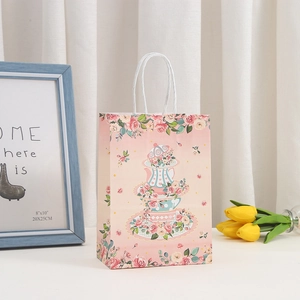 Detalle de bolsa de regalo rosa floral con asa de cuerda retorcida blanca reforzada
