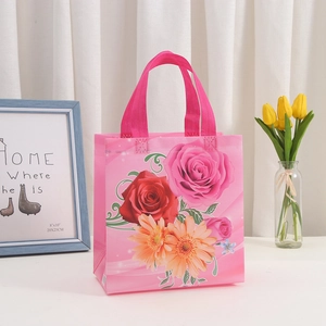 Macro view of a pink floral non-woven gift bag with vibrant roses and gerbera daisy prints