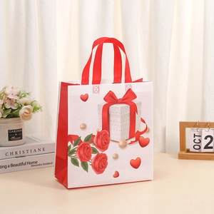 Détail d'un sac cadeau blanc en intissé avec motif de rose et anses rouges élégantes