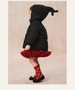 Detail of kids black hooded puffer jacket with cute ear accents and red tutu dress