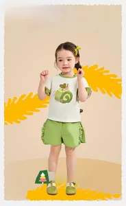 Détail de l'ensemble d'été fille avec volants verts sur t-shirt crème et short assorti