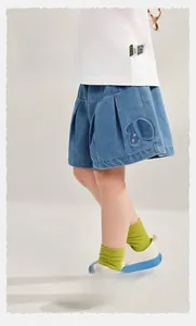 Detail of girls' blue denim shorts with butterfly embroidery and soft pleated fabric