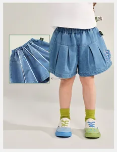 Detail of girls' pleated denim shorts featuring butterfly embroidery and elastic waistband