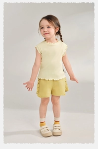 Détail du haut jaune côtelé et du short en coton à volants pour petites filles