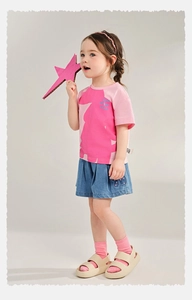 Detail of girls' summer outfit featuring a pink graphic T-shirt and denim pleated shorts