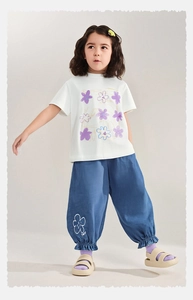 Dettaglio completo estivo bambina con maglietta floreale bianca e pantaloni blu
