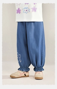 Dettaglio di pantaloni larghi in denim per bambina con volant elastico e fiori