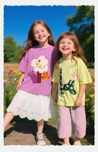 Dos niñas con camisetas de algodón con estampados en color morado y amarillo en el campo