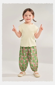 Detail of kids breathable summer trousers featuring abstract green and pink dot patterns