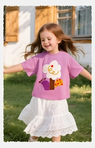 Niña con camiseta de algodón morada con estampado floral corriendo en el césped