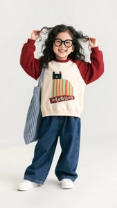 Detailed view of girls casual outfit featuring raglan sweatshirt and wide-leg denim jeans