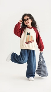 Detailed view of girls casual wide leg jeans paired with a red patchwork sweatshirt