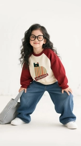 Detail of girls red raglan sweatshirt with cat print and vintage blue wide leg jeans
