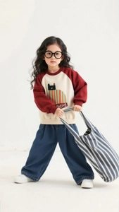 Detail shot of girls color-block sweatshirt with cartoon cat and navy wide-leg jeans