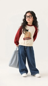 Detail of girls' casual outfit featuring a cat print sweatshirt and wide-leg denim jeans