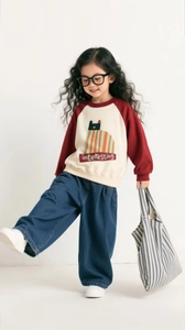 Detail showing the red raglan sleeves and cute cartoon cat print on the girls sweater