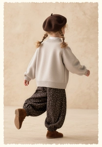 Detail of girls floral autumn trousers paired with knit sweater and baret in cozy setting